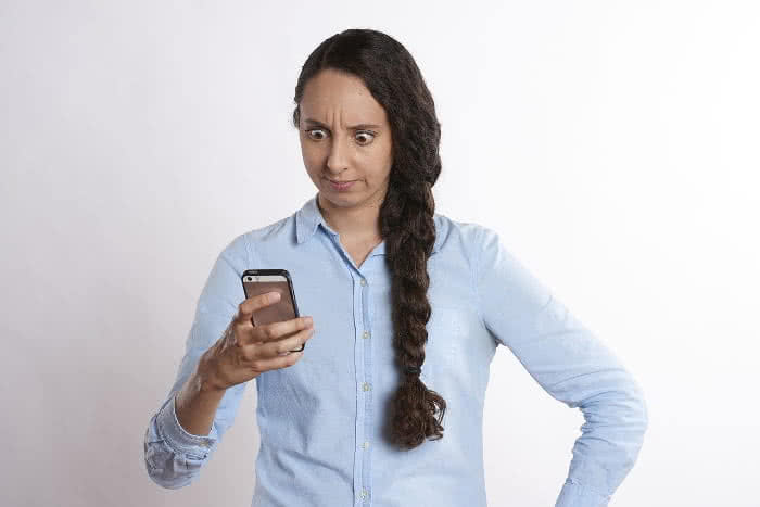 Frau mit iPhone in der Hand ärgert sich